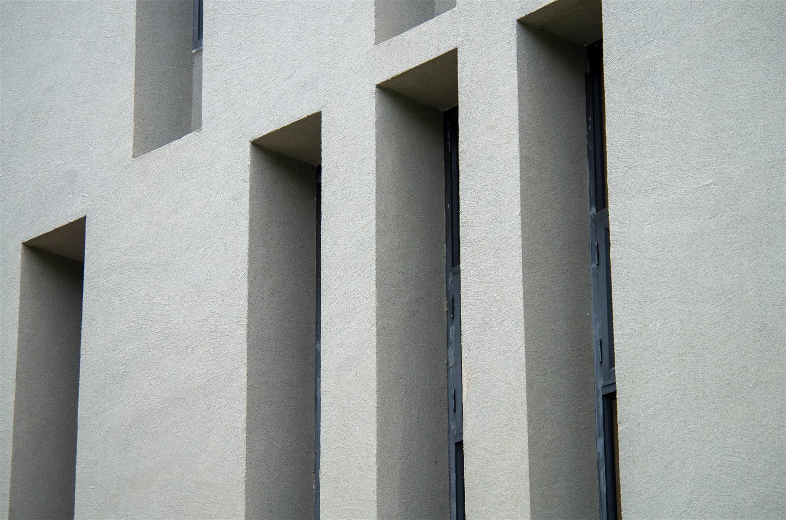 Texture finish continuing around deep institutional window reveals